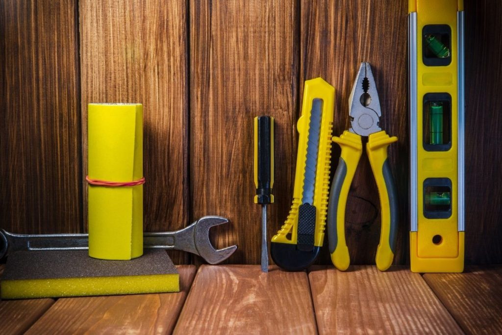 An assortment of tools displayed on a wooden background, featuring a clear area for text or other content.